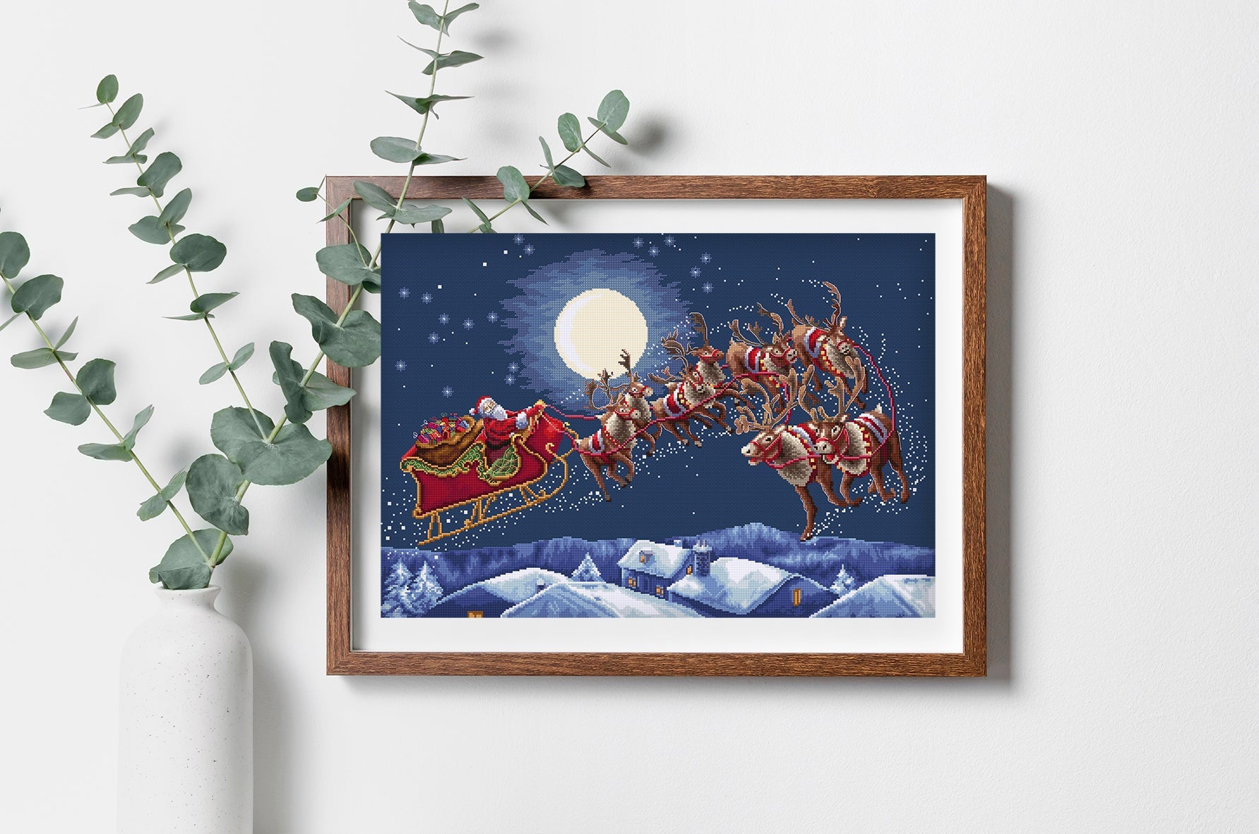 Framed artwork of Santa Claus in a sleigh with reindeer against a night sky with a full moon.