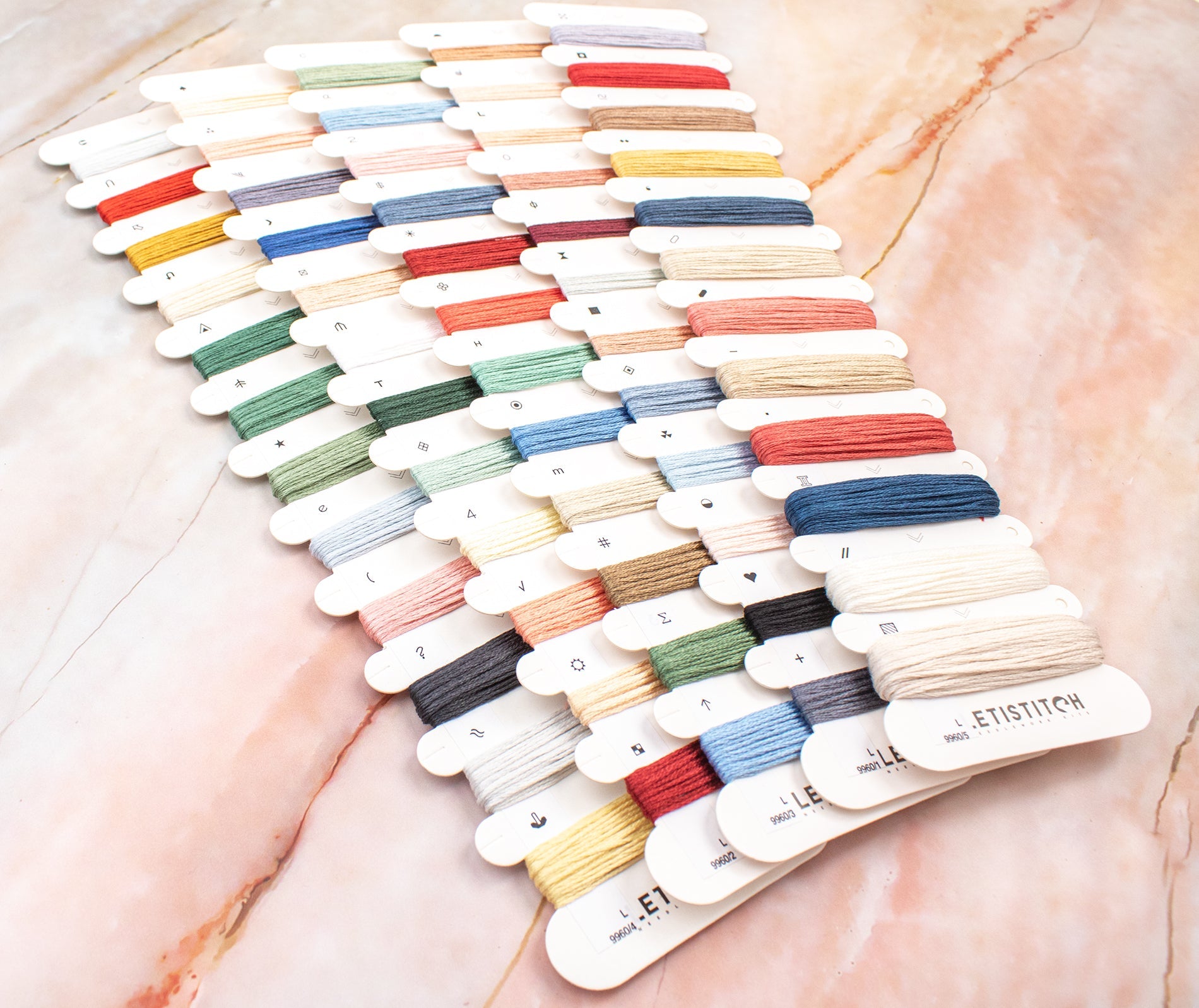 Color swatch card with various thread colors on a marble surface