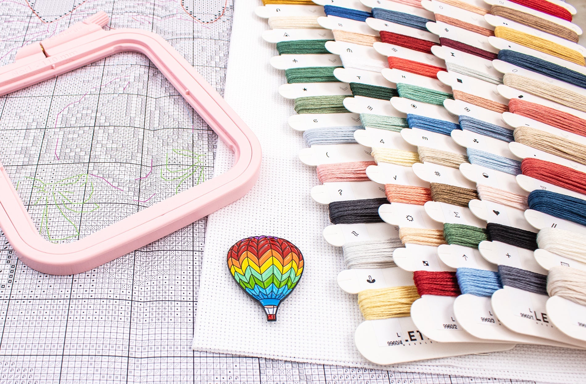 Colorful embroidery hoop and spools of thread on a grid background