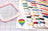 Colorful embroidery hoop and spools of thread on a grid background
