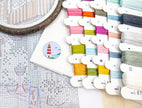 Colorful embroidery threads on a cross-stitch chart with an embroidery hoop.