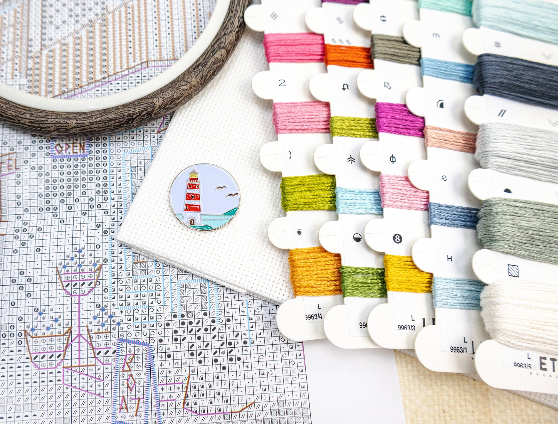 Colorful embroidery threads on a cross-stitch chart with an embroidery hoop.