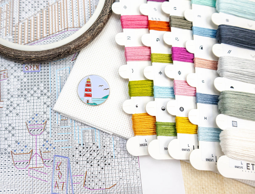 Colorful embroidery threads on a cross-stitch chart with an embroidery hoop.