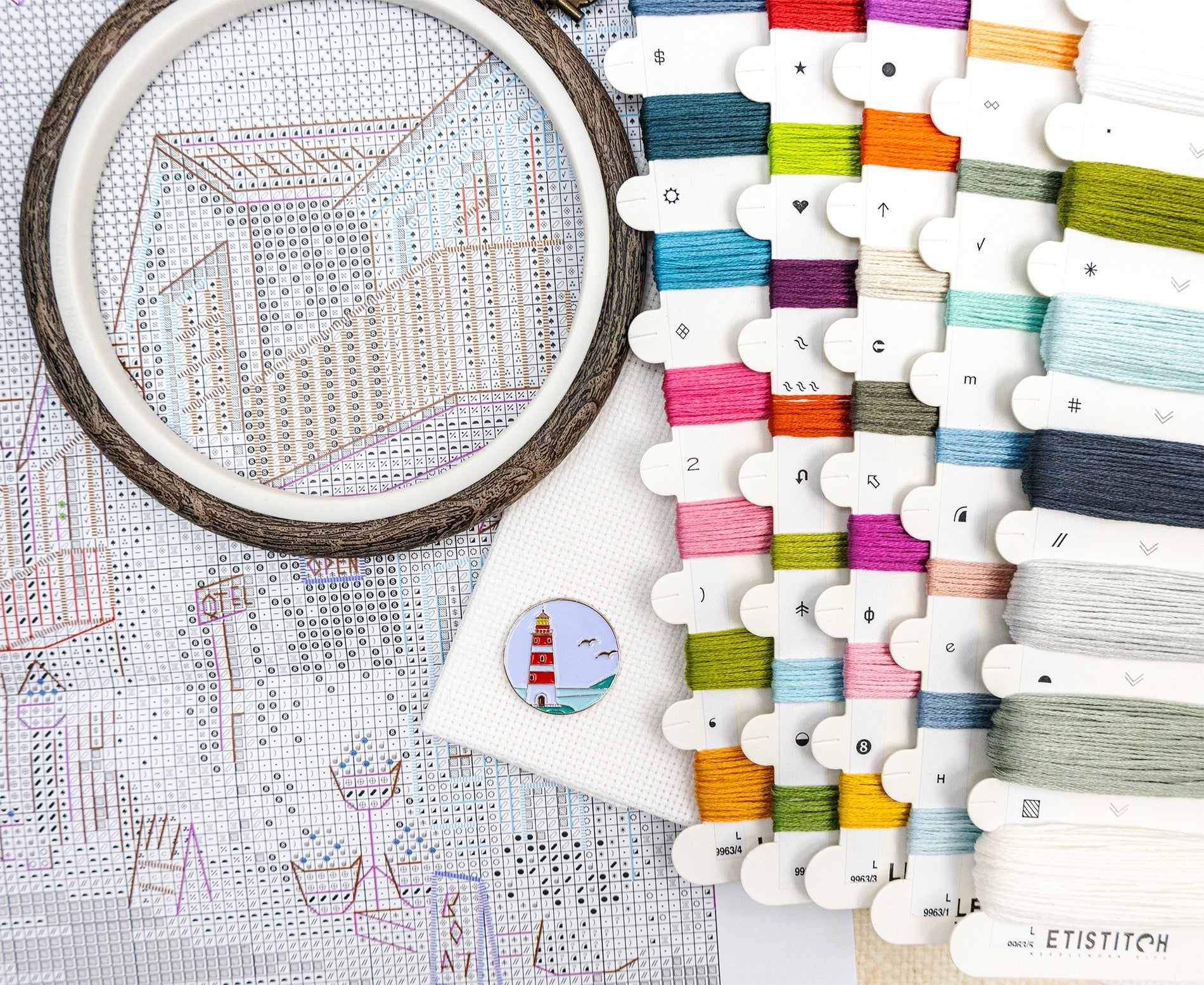 Embroidery hoop with partially completed design and spools of thread on a table.