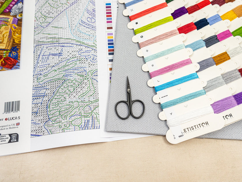 Color swatch, fabric swatches, and a pair of scissors on a table