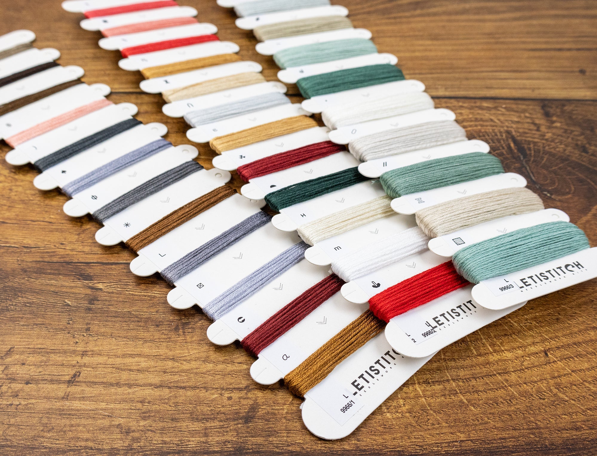 Color swatch cards with embroidery threads on a wooden surface