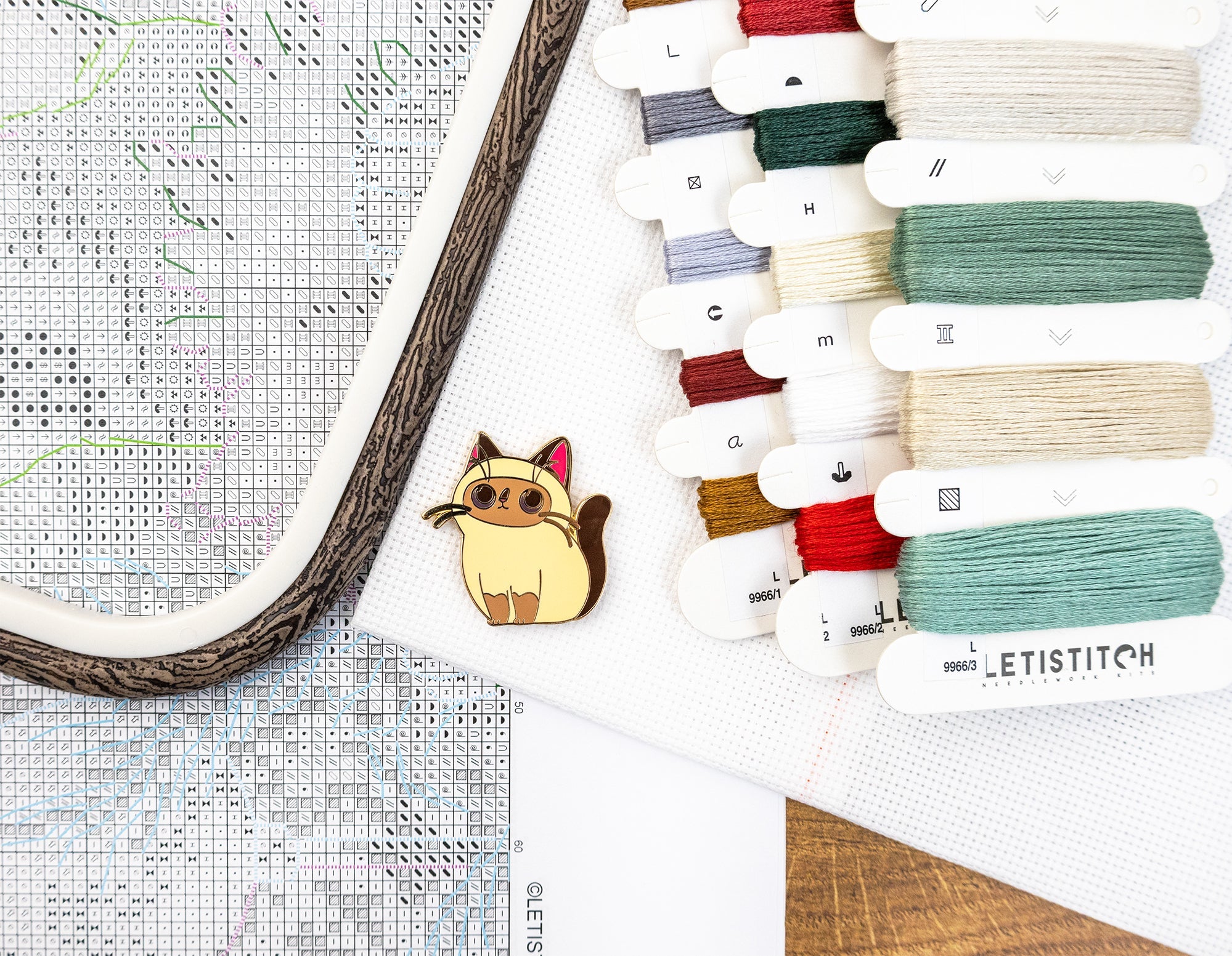 Collection of embroidery threads and a cross-stitch hoop on a wooden surface.