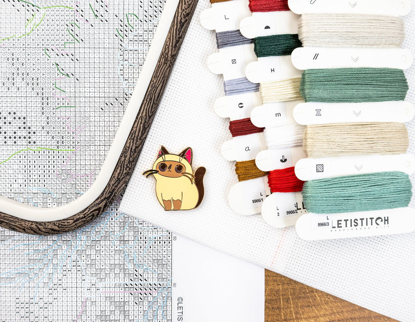 Collection of embroidery threads and a cross-stitch hoop on a wooden surface.