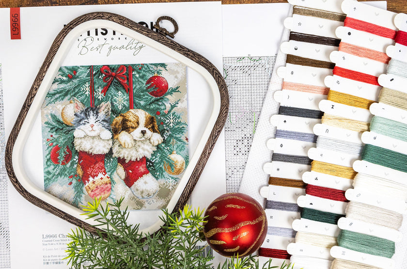 Cross-stitch kit with a Christmas-themed design, threads, and a ruler on a white background.