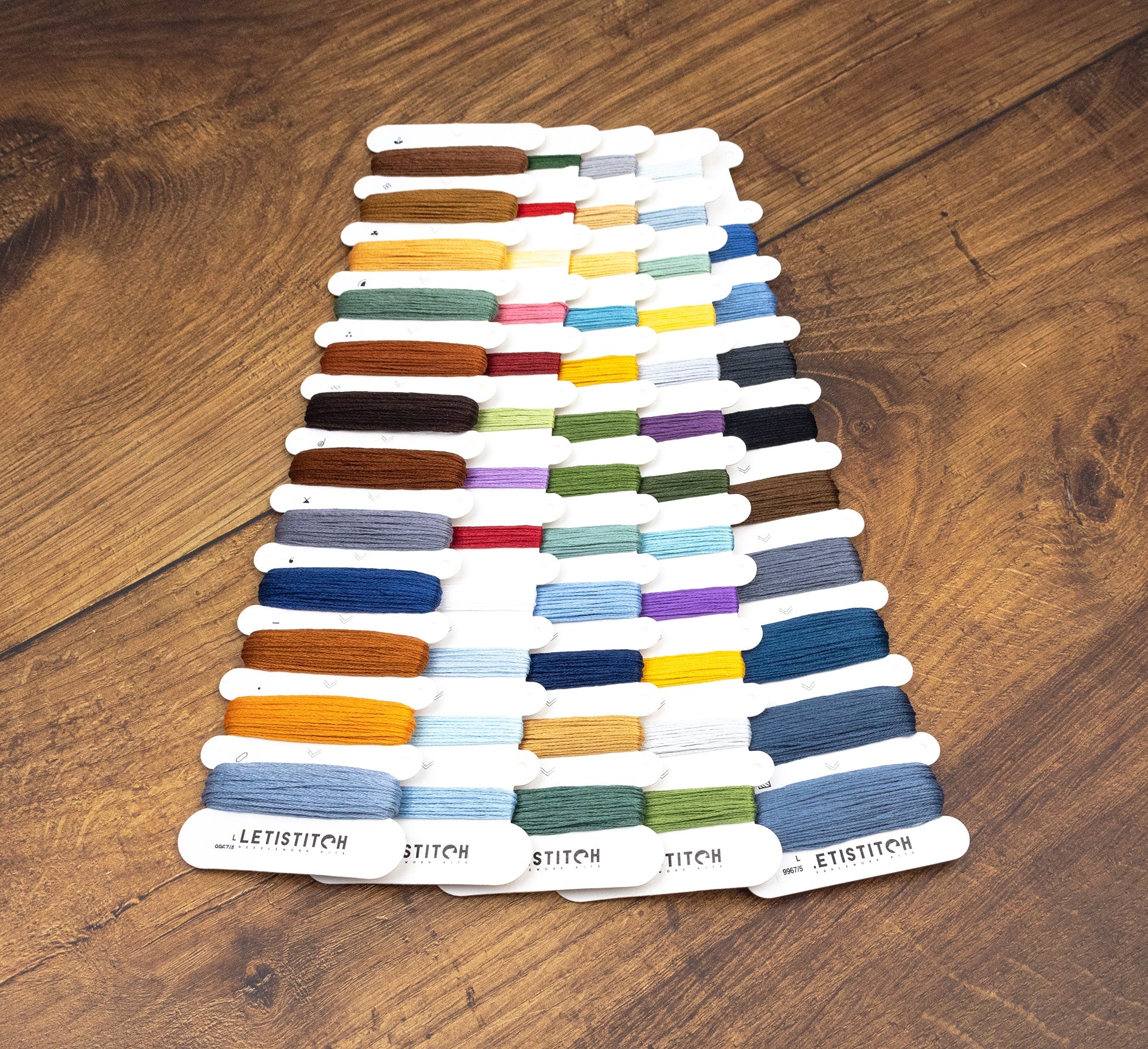 Color swatch card with various threads on a wooden surface