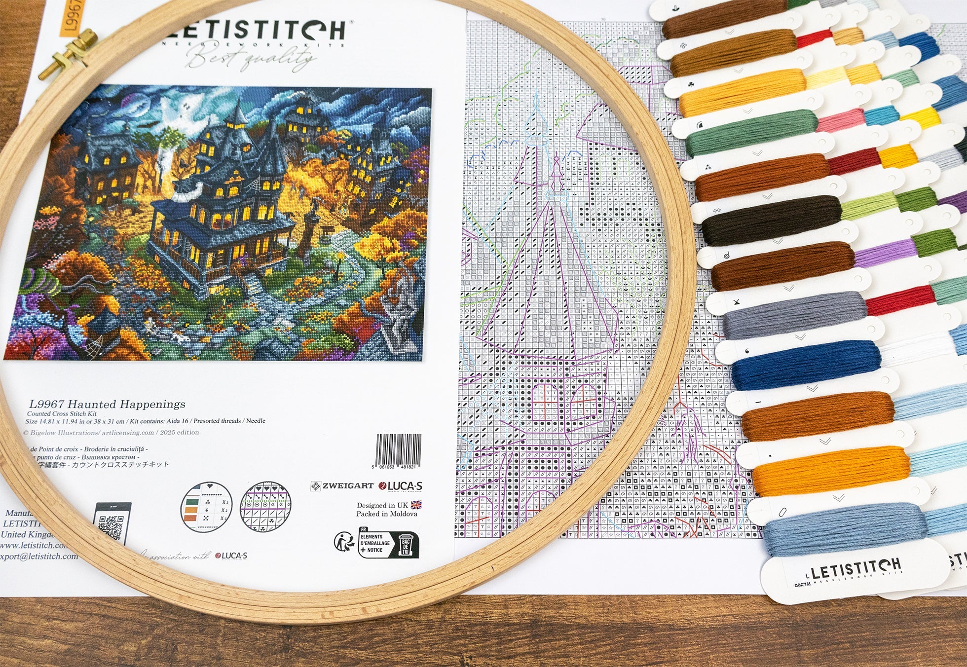 Embroidery hoop with cross-stitch pattern and color chart on a wooden surface