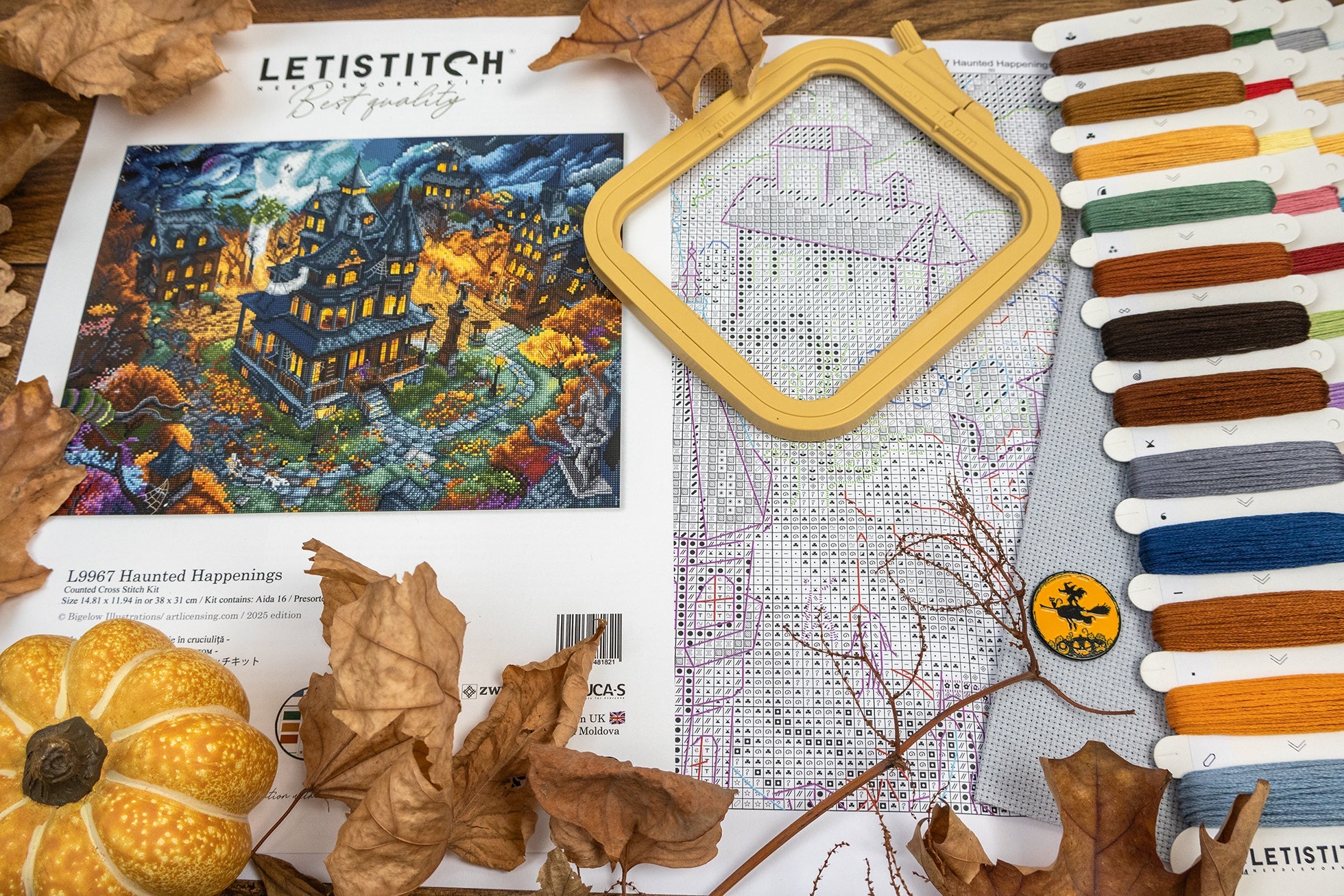 Cross-stitching kit with fabric, threads, and a pumpkin decoration on a wooden surface.