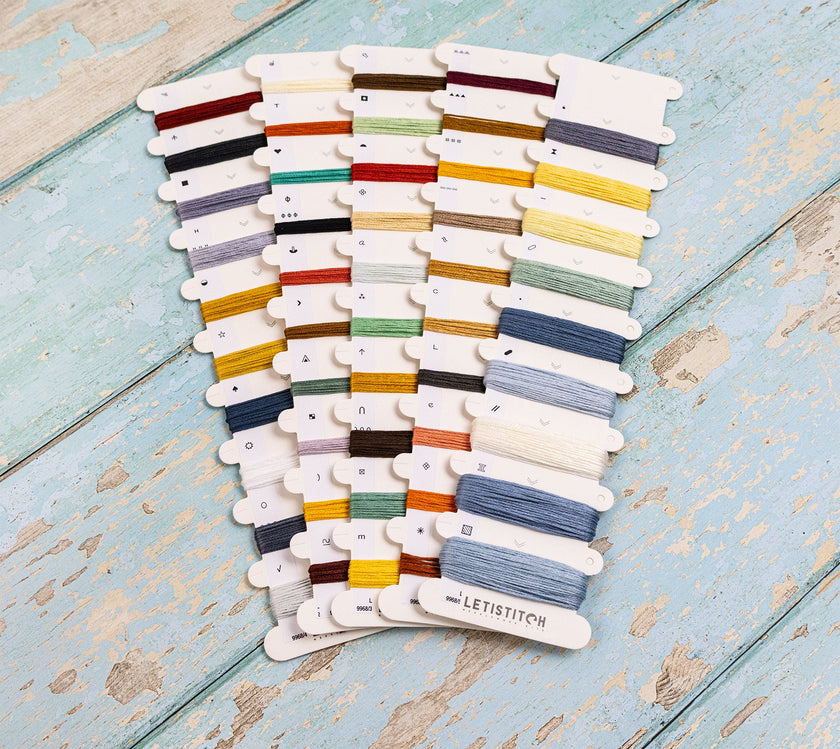 Set of colorful embroidery threads on cards with 'Letistitch' branding on a wooden surface.