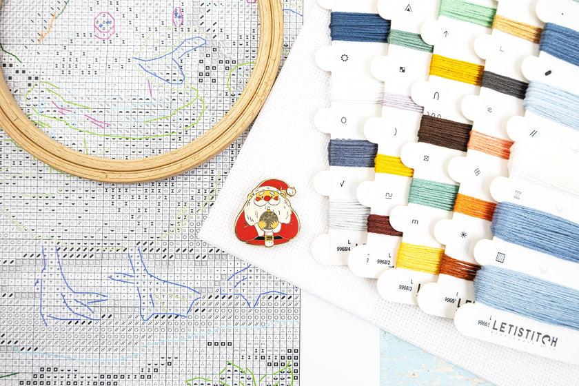 Cross-stitching kit with embroidery hoop, thread, and pattern sheet on a white background