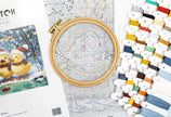 Cross-stitching kit with embroidery hoop, pattern, and color chart on a white surface.
