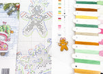 Cross-stitch pattern with gingerbread man design and colorful threads on a white background