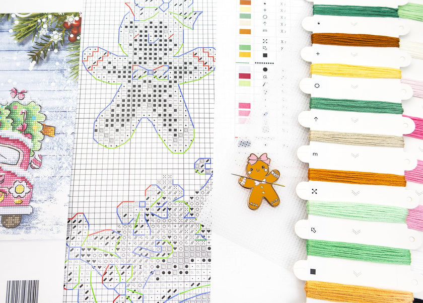 Cross-stitch pattern with gingerbread man design and colorful threads on a white background