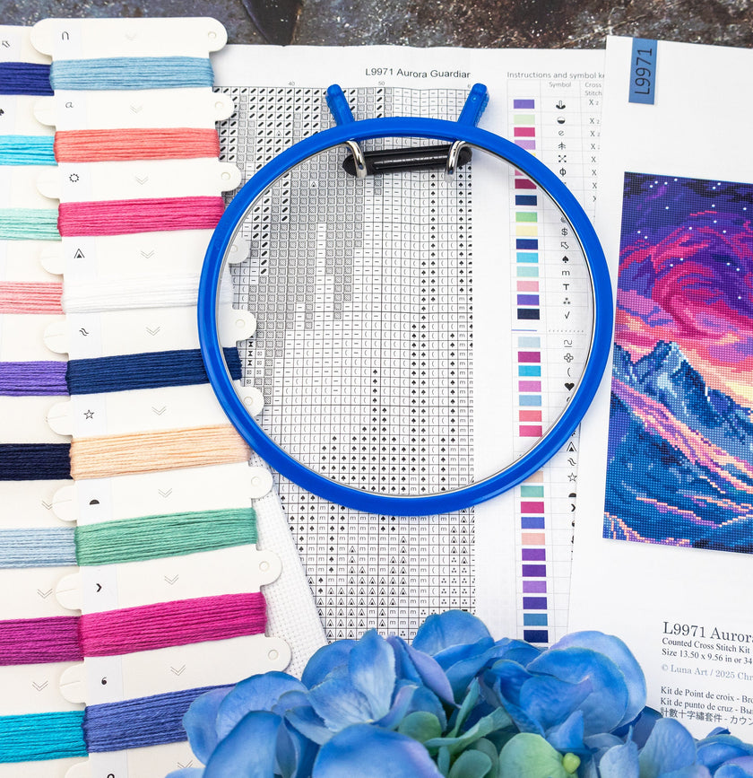 Embroidery hoop with cross-stitch pattern and fabric swatches on a table