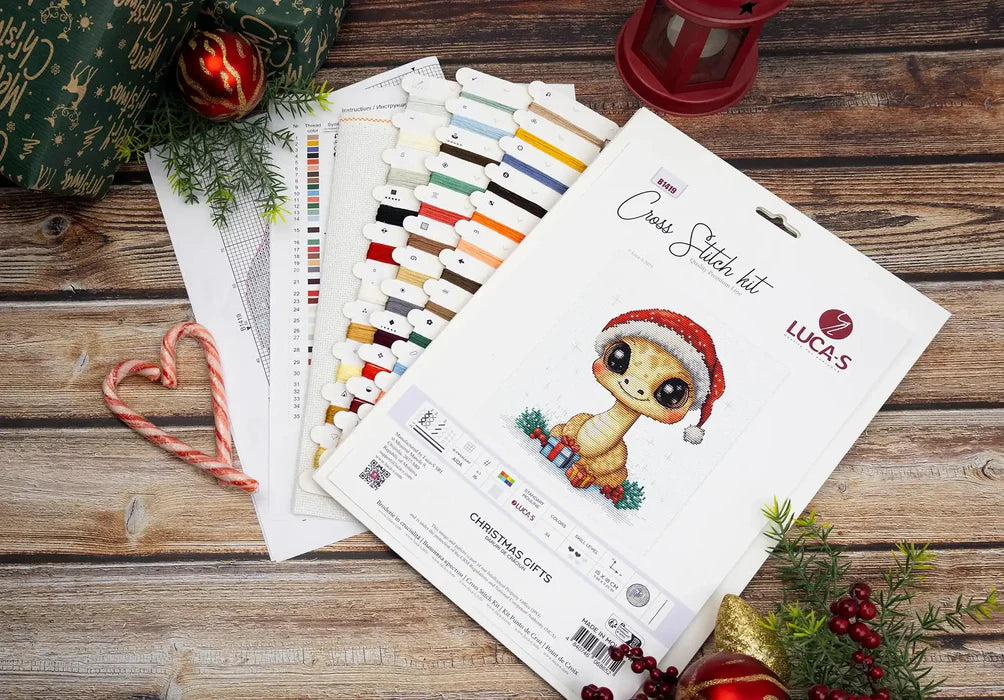 Embroidery kit with a Christmas-themed design on a wooden surface with festive decorations.