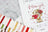 Cross stitch kit with a teddy bear design and 'I love you' text, surrounded by threads and a cross stitch chart.