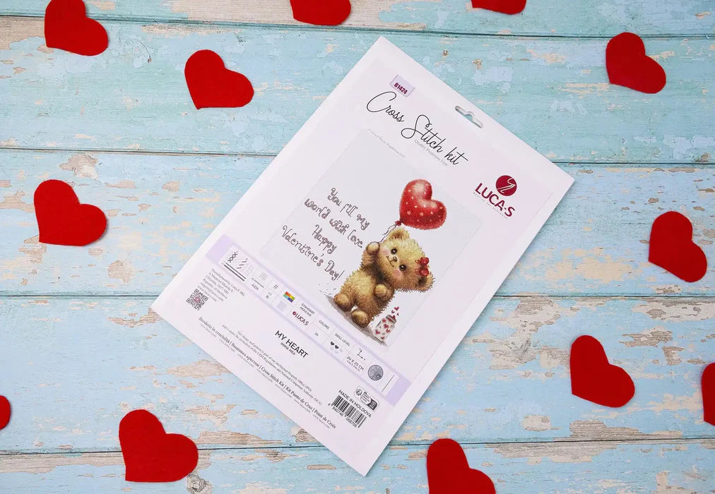 Card with teddy bear illustration on a blue wooden surface with red heart decorations