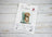 Cross stitch kit packaging with a dog and boot illustration on a wooden surface