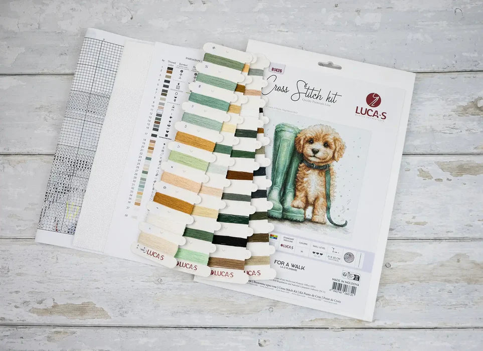 Cross stitch kit with pattern chart and dog illustration on a wooden surface