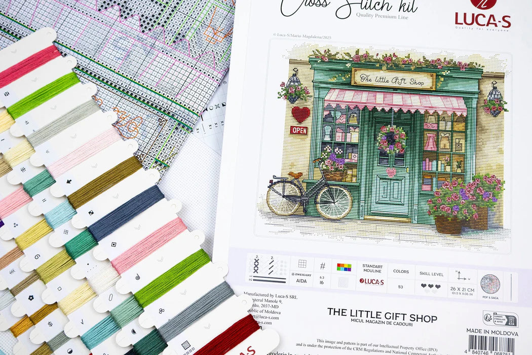 Cross stitch kit with pattern chart, thread colors, and packaging featuring 'The Little Gift Shop'.