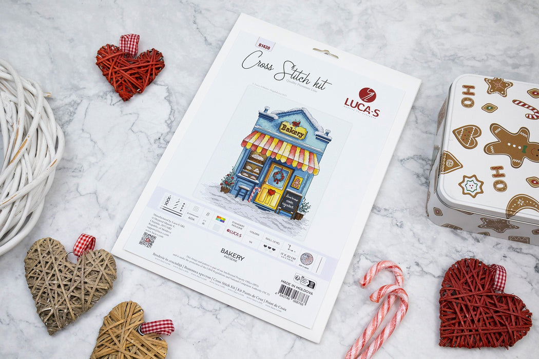 Cross-stitch kit with packaging and decorative hearts on a marble surface