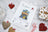 Cross-stitch kit with packaging and decorative hearts on a marble surface