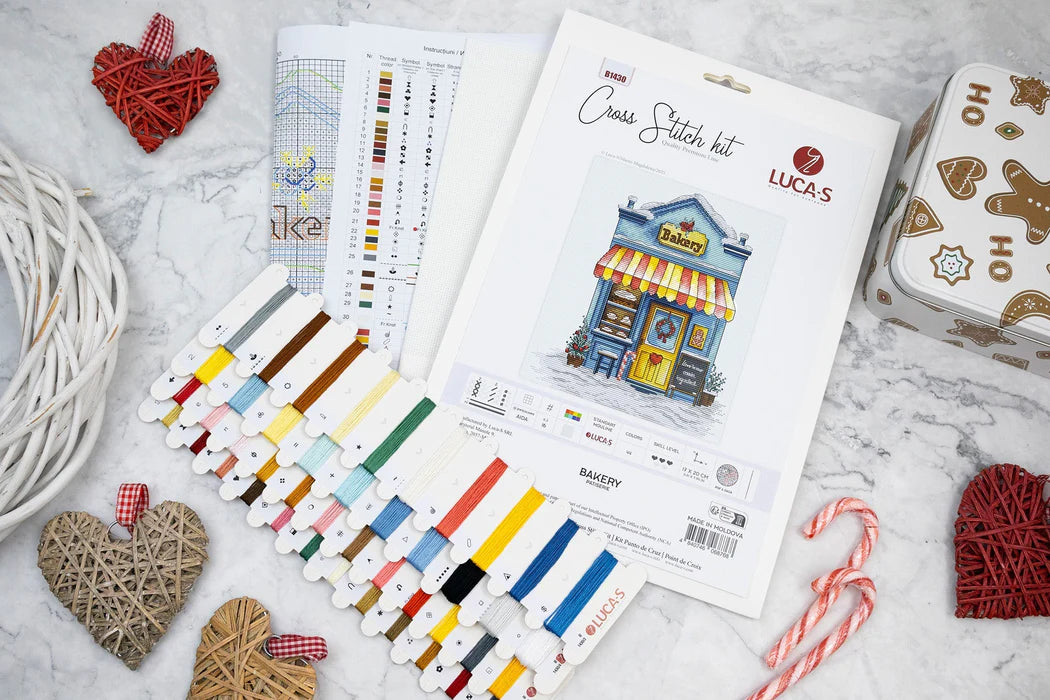 Cross stitch kit with colorful threads and pattern chart on a textured surface.