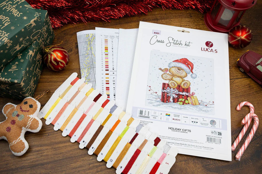 Cross stitch kit with color chart and Christmas-themed decorations on a wooden surface