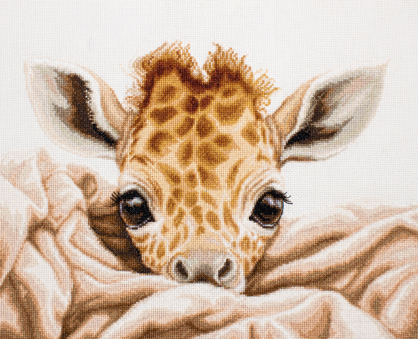 Cross-stitched pattern of a baby giraffe peeking over a blanket