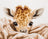 Cross-stitched pattern of a baby giraffe peeking over a blanket