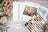 Embroidery kit with floral pattern, threads, and color chart on a wooden surface.