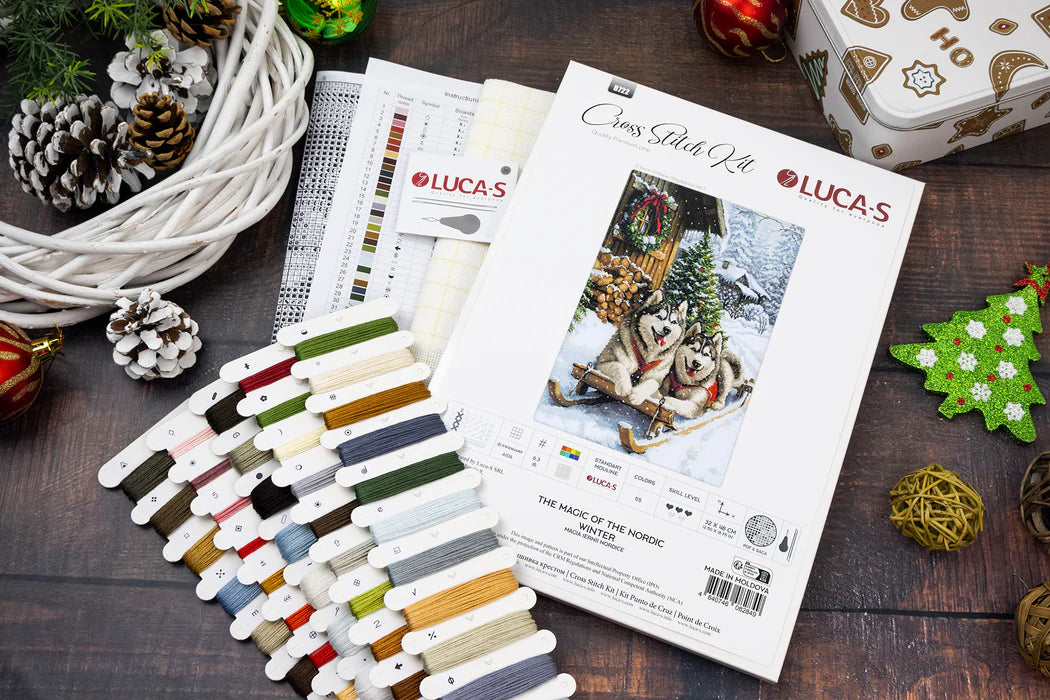 Lucas embroidery kit with threads and pattern on a wooden surface with Christmas decorations.