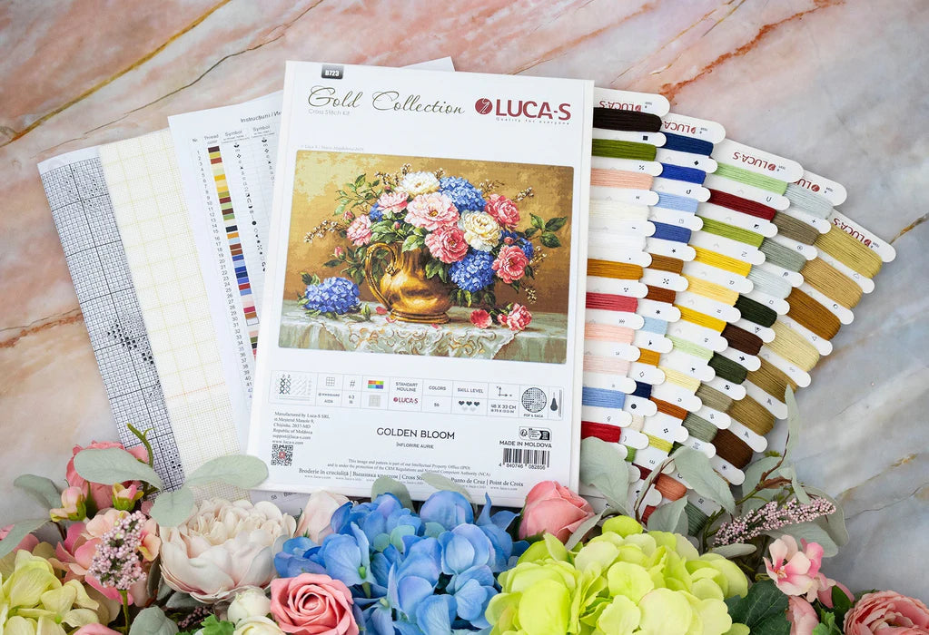 Cross-stitch kit with floral design and color swatch on a marble surface