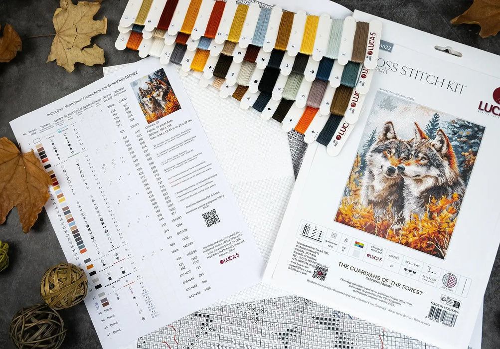 Cross stitch kit with pattern chart and wolf design on a textured surface.