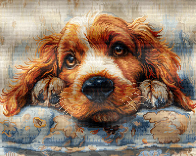 Cross-stitched or embroidered picture of a dog on a cushion with paw prints.