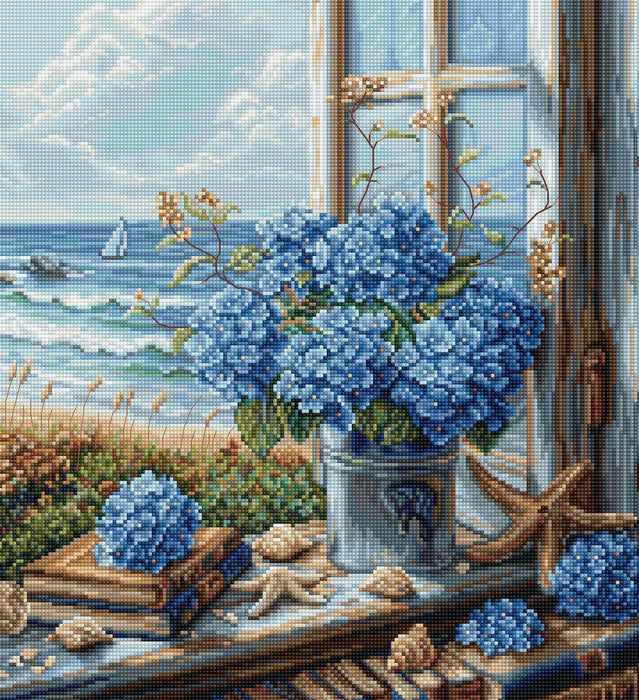 Cross-stitched scene with blue flowers, books, and a window overlooking the sea.