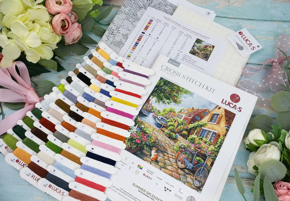 Cross stitch kit with color chart and floral decorations on a wooden surface