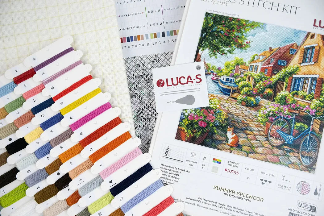 Color swatch book, patterned paper, and Luca-S paint set with a scenic painting on a white surface.
