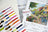 Color swatch book, patterned paper, and Luca-S paint set with a scenic painting on a white surface.