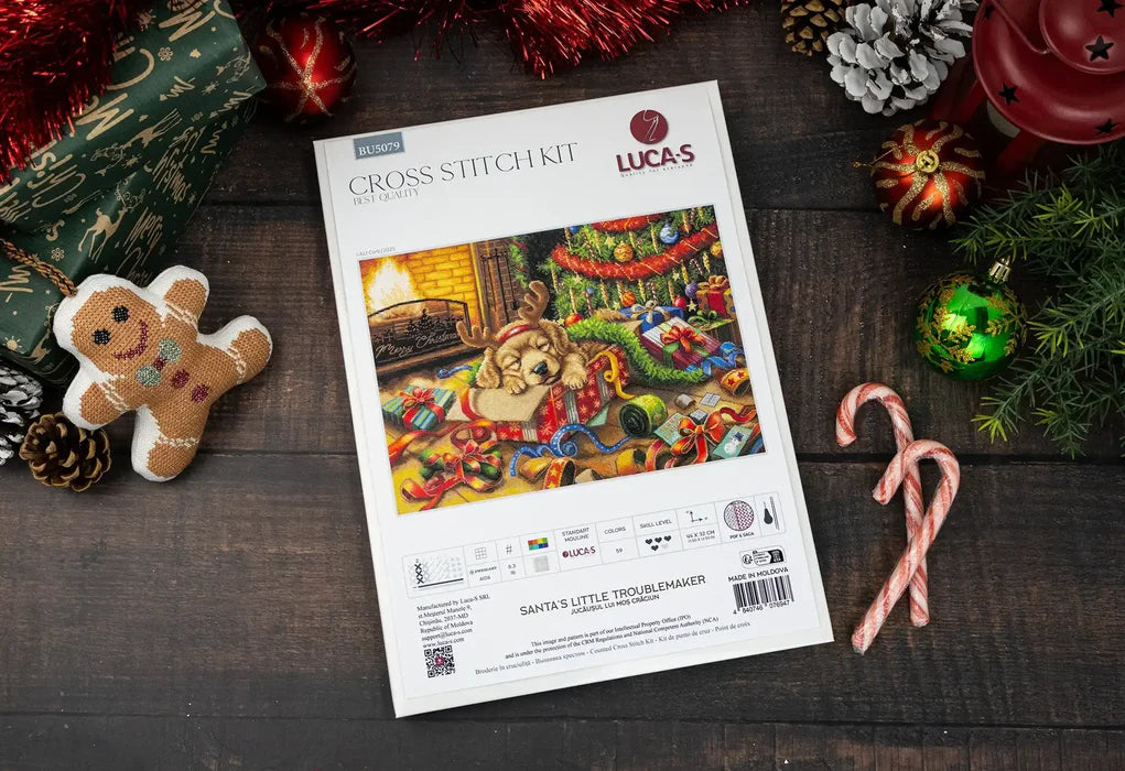 Lucas cross-stitch kit packaging with Christmas-themed decorations on a wooden surface