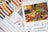 Cross stitch kit with color chart, pattern book, and thread set on a white background