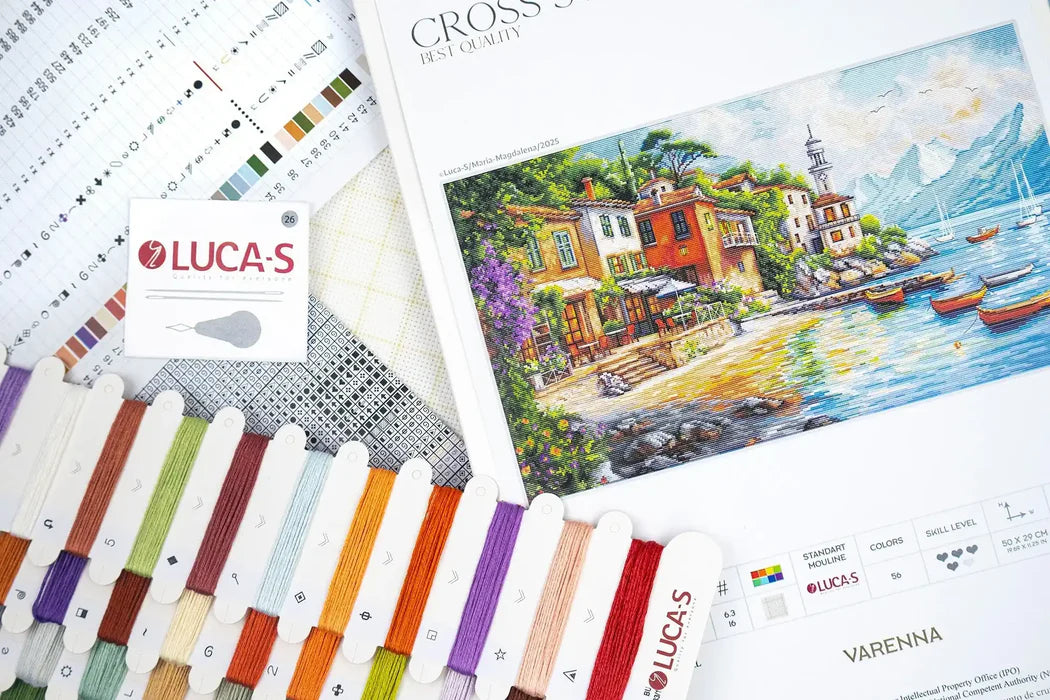 Color chart and thread spools with a scenic painting of a village by a lake, featuring the brand 'Lucas'.
