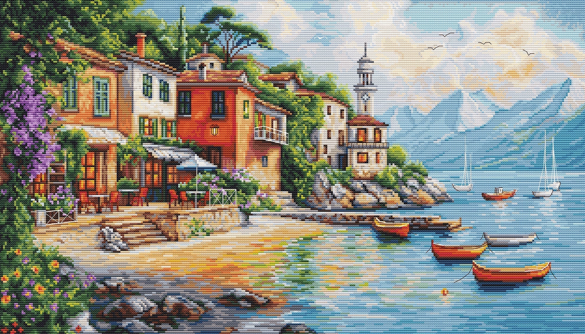 Stitched cross stitch of a coastal scene with houses, boats, and mountains.