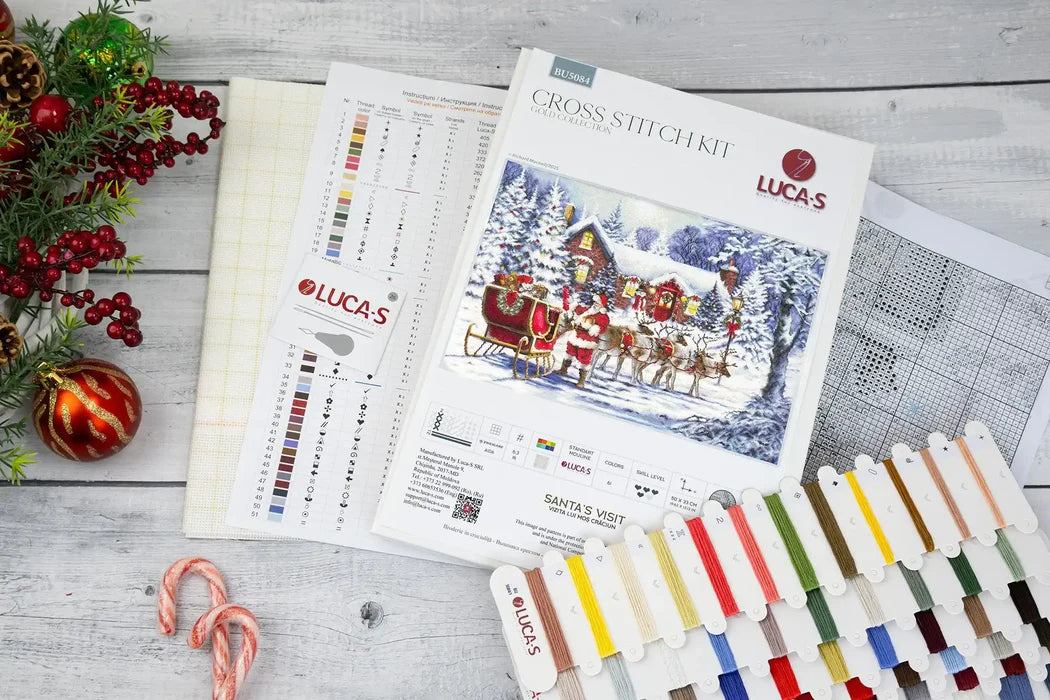 Lucas cross-stitch kit with color chart and Christmas-themed decorations on a wooden surface