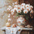 Still life with white flowers, a decorative vase, and shells on a wooden surface.