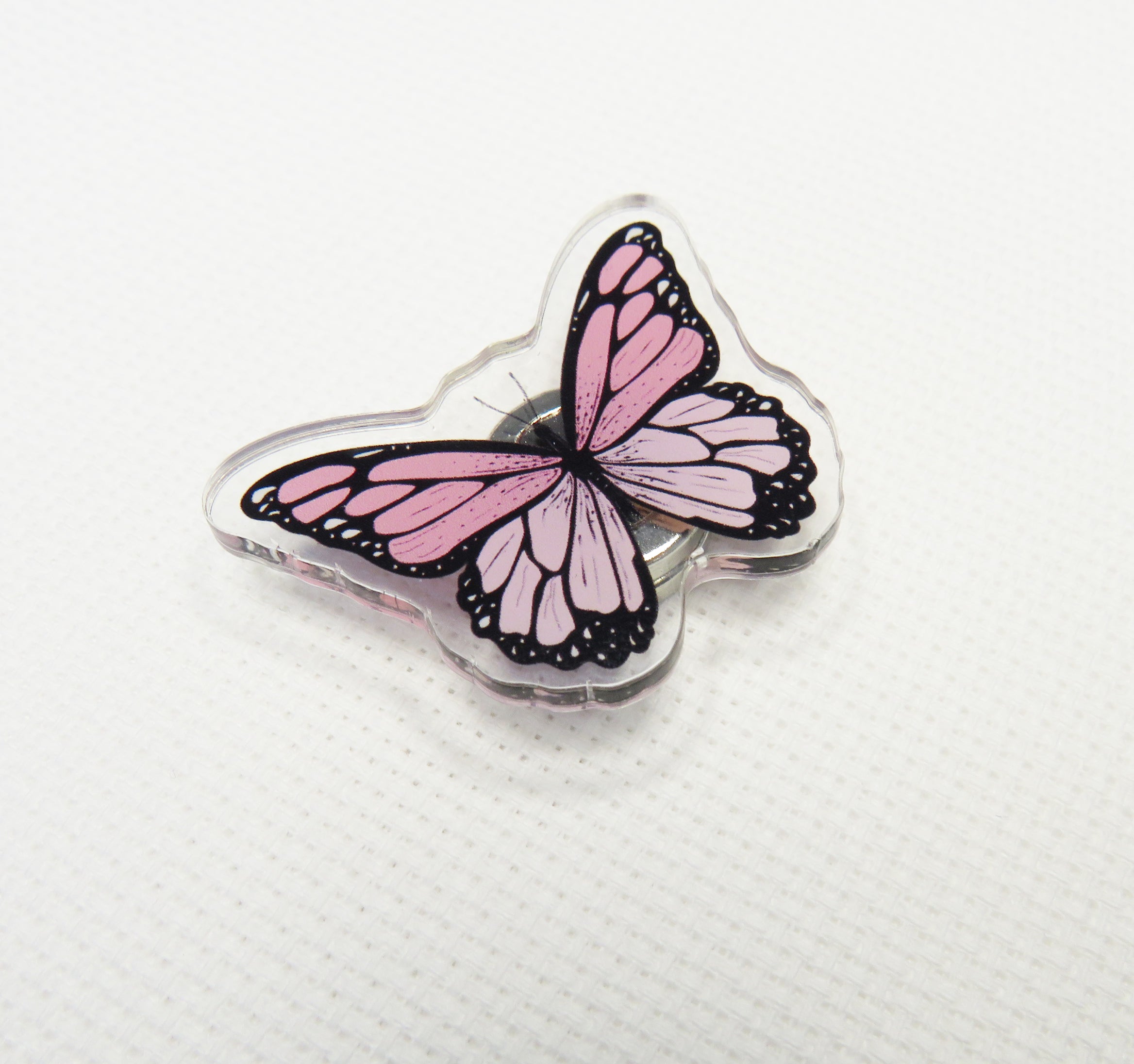 Butterfly-shaped needleminder with pink wings on a white background